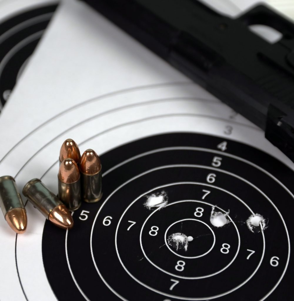 gun-and-many-bullets-shooting-targets-on-white-table-in-shooting-range-polygon-training-for-aiming.jpg